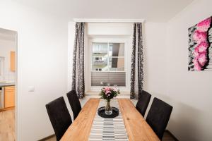 a dining room table with black chairs and a vase of flowers at Leonhardsblick Appartements in Tamsweg