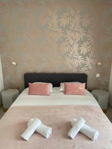 two towels on a bed with pink and tan wallpaper at Le Nid du Faubourg in Beaune