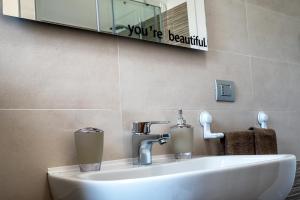 a bathroom sink with a mirror and a sign that reads youre beautiful at Marco's House in Alghero +26 photos