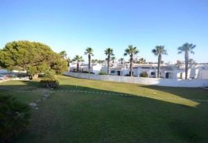 einen Golfplatz mit Palmen und ein Gebäude in der Unterkunft Stupendo Appartamento a Cala’n Bosch Minorca in Cala'n Bosch