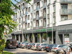 uma longa fila de carros estacionados em frente a um edifício em 3L Apartments Nadmorskie Tarasy em Kolobrzeg