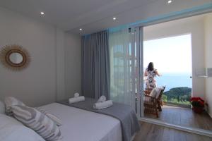 een vrouw in een slaapkamer met uitzicht op de oceaan bij Lakones Deluxe Suites A in Lákones