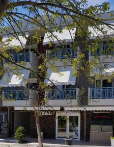 un edificio blanco con ventanas azules y un árbol en Royal Studios, en Kallithea Halkidikis