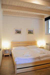 1 dormitorio con 1 cama grande con sábanas blancas en Apartmány Deluxe, en Sázava