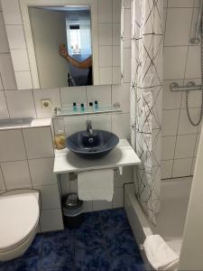 ein Badezimmer mit einem Waschbecken, einem WC und einem Spiegel in der Unterkunft Gästehaus Sylvie in Rust