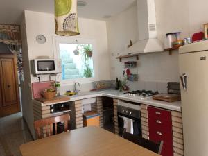 cocina con nevera y mesa. en Casa Taller Penelles, en Penellas