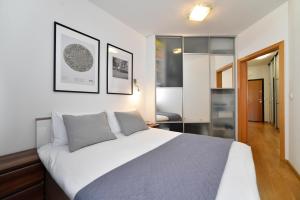 een slaapkamer met een groot wit bed en een aantal foto's aan de muur bij BLOCK APARTMENT PARK with private garage parking in Zagreb