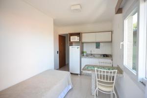 a small kitchen with a table and a refrigerator at Pousada Villa Maciel in Bombinhas