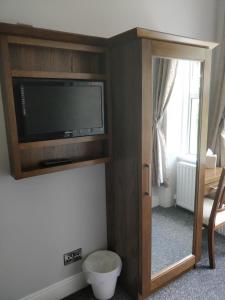 ein Wohnzimmer mit einem TV und einem Spiegel in der Unterkunft Arkle House in Pennyburn