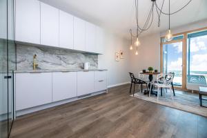 a kitchen with white cabinets and a table with chairs at Modern spacious studio w/ Sea Views in Klaipėda +12 photos