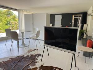 een woonkamer met een grote televisie en een tafel bij Leen & Bruno's NamaStay in Grez-Doiceau