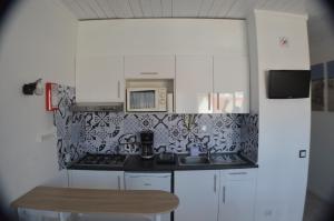 a small kitchen with a microwave and a sink at Joli studio rénové Emplacement idéal front de mer in Cabanas de Tavira