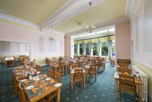 a dining room with tables and chairs and windows at The Glenburn Hotel in Rothesay