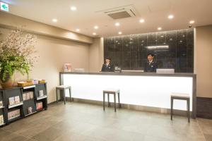 two men standing behind a counter in a lobby at Kuretake Inn Nagoya Hisayaodori in Nagoya