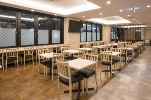 a dining room with tables and chairs and windows at Kuretake Inn Nagoya Hisayaodori in Nagoya