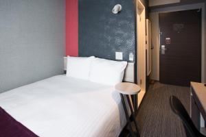 a room with a bed and a table and a door at Kuretake Inn Nagoya Hisayaodori in Nagoya