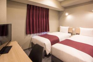 a hotel room with two beds and a flat screen tv at Kuretake Inn Nagoya Hisayaodori in Nagoya