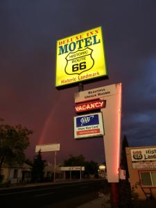 Una señal para un motel con un arco iris en el cielo en Deluxe Inn, en Seligman