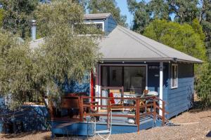 a blue tiny house with a porch and a table at Bandalong Cottages in Mudgee