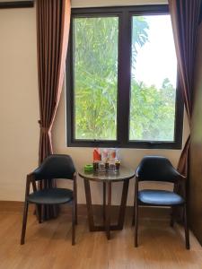 Zimmer mit einem Tisch, 2 Stühlen und einem Fenster in der Unterkunft Khách Sạn Hoàng Gia II in Thái Bình