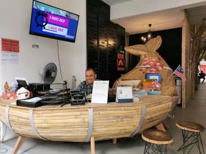 a man sitting at a counter in front of a wooden boat at Leo Backpackers @ Central Market in Kuala Lumpur
