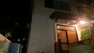 ein Haus mit einer Tür mit einem Tor in der Nacht in der Unterkunft The Sloope Nagasaki in Nagasaki