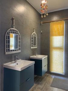 ein Bad mit 2 Waschbecken, einem Spiegel und einem Fenster in der Unterkunft Ash Villa in Al Sharqiyah