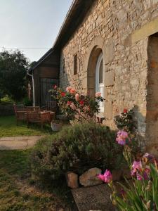 una casa de piedra con un banco y flores en el patio en Chambre d'hôtes La Ruzardière, en Combourtillé