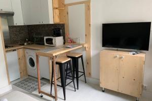 una cucina con tavolo, sgabelli e TV di Charmant petit studio en centre ville a Bastia