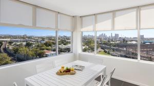 a dining room table with a window overlooking a city at Oaks Brisbane Woolloongabba Suites in Brisbane