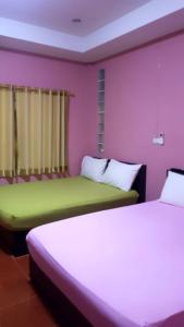 two beds in a room with purple and green at สุขกมลรับอรุณแฝด2ห้อง in Chanthaburi