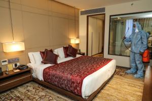 un hombre está de pie en una habitación de hotel con una cama en Sayaji Vadodara, en Vadodara