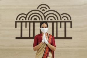 una mujer con una máscara facial rezando delante de una pared en Sayaji Vadodara, en Vadodara