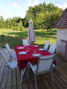 a red table with chairs and an umbrella on a deck at Yourte mongole véritable in Montcaret