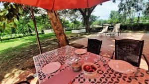 una mesa con una sombrilla roja y una mesa con comida en Kampu Nature Pool Villa Rayong, en Rayong