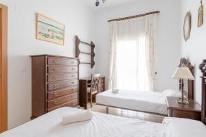 een slaapkamer met 2 bedden, een dressoir en een raam bij Villa Gallardo in Campillos