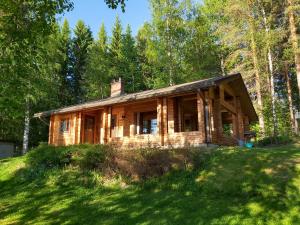 a log cabin on a hill in the woods at Kuhajärven Suviranta cottage in Vihtavuori