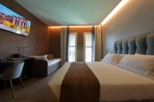 a bedroom with a bed and a desk and a tv at Hotel Bell'arrivo by Dori in Peschiera del Garda