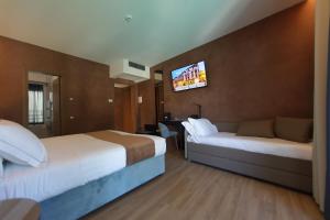 a hotel room with two beds and a flat screen tv at Hotel Bell'arrivo by Dori in Peschiera del Garda