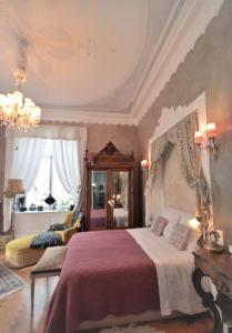 a bedroom with a large bed and a chandelier at Castelnau in Colmar