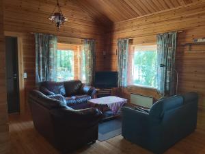 a living room with two leather couches and a table at Kuhajärven Suviranta cottage in Vihtavuori