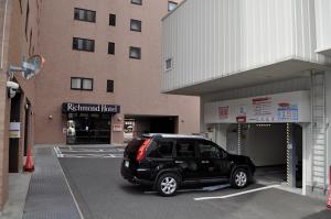a black car parked in a parking lot next to a building at Richmond Hotel Sendai in Sendai