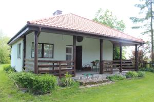 a small white house with a porch and a table at Domek w NABO in Załuski +22 photos
