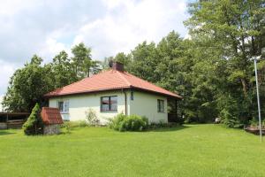 a small white house with a red roof in a yard at Domek w NABO in Załuski