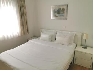 1 dormitorio con 1 cama blanca con sábanas y almohadas blancas en Apartments Dvor - ap1, ap2, ap3, en Baška Voda