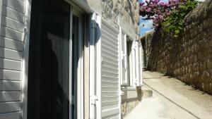 ein Schatten einer Person, die aus dem Fenster auf ein Gebäude blickt in der Unterkunft Eco Apartments Kate in Suđurađ