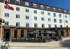 a large white building with tables and umbrellas at Hotel Svendborg in Svendborg
