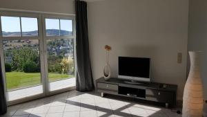 a living room with a tv and a large window at Ferienwohnung Gockels-Auszeit in Bad Wildungen