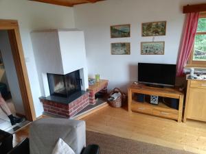 a living room with a fireplace and a television at Auerberg Blick in Hainfeld