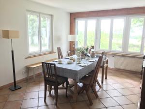 a dining room with a table and chairs and windows at B&B Domaine En Trembley in Commugny